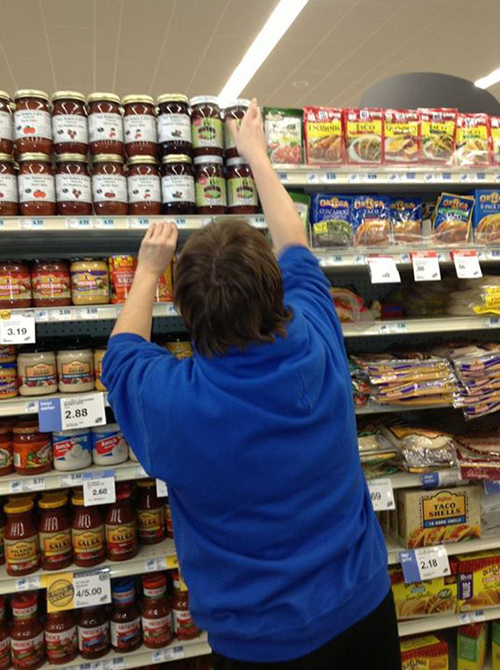 Lisa stocking 6C's Salsa on the shelf.